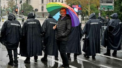 Der Belgrader Pride-Organisator Goran Miletic hält während eines Pride-Marsches am 17. September 2022 in Belgrad einen Regenbogenschirm hinter Polizisten Verbot einer Europride-Parade durch die Behörden, was Ängste vor möglichen Unruhen schürt. (Foto von Andrej ISAKOVIC / AFP)